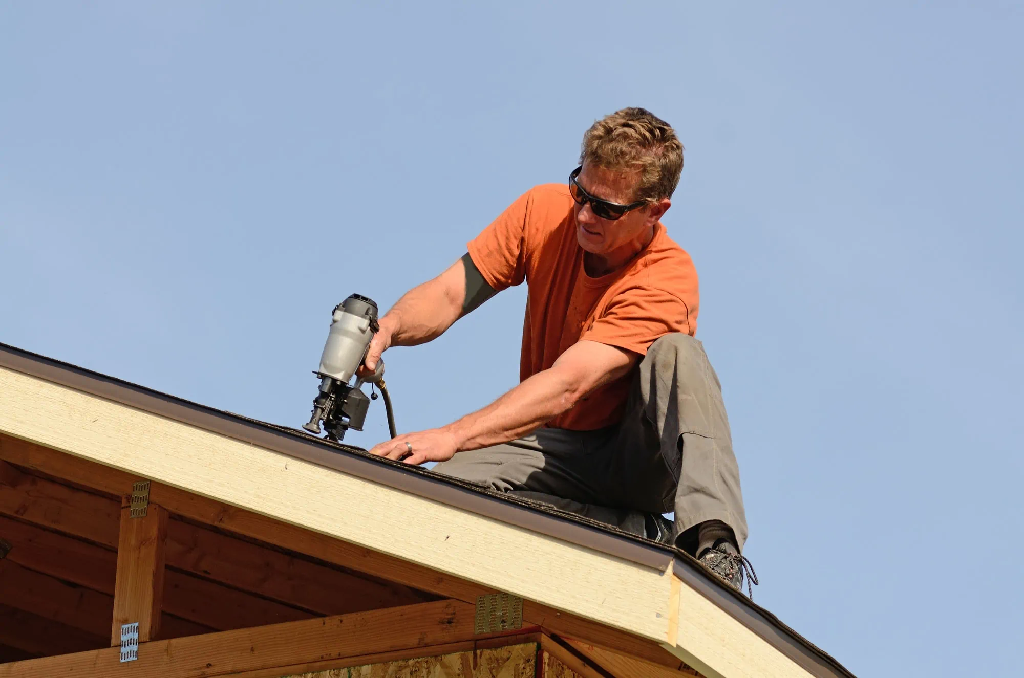 A man installing roof tiles with a nail gun.