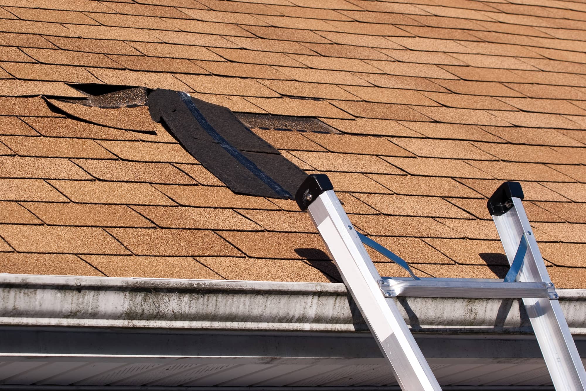 Damaged roof shingles repair process.