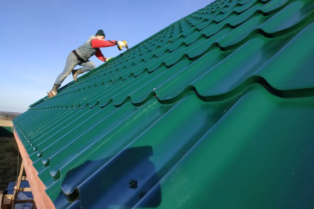 a rooftop worker attaches a metal tile to the roof base.